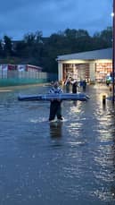 Staff from Kukoon carry rugs away from their flooded premises.