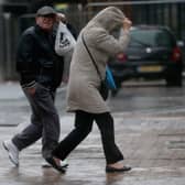 People walk in rain and high winds.