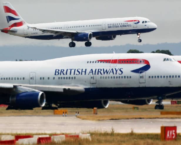 A British Airways plane lands as two other grounded planes sit on the runway at Heathrow Airport.