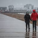 A couple walk in heavy rain on the South Parade Pier, in Portsmouth.