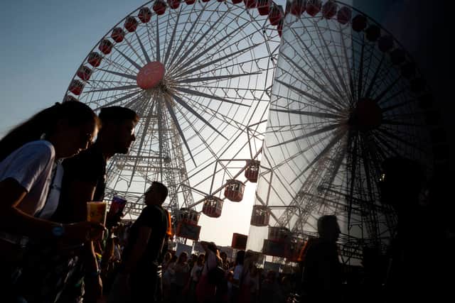 People walk next to a Ferris wheel during the Rock in Rio Lisboa music festival at Bela Vista Park in Lisbon, on June 24, 2018.