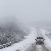 Car drives along snowy road.