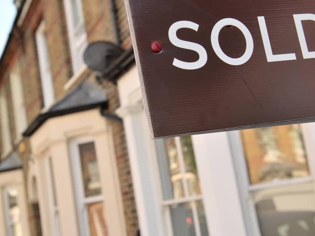 An estate agent's "sold" board stands outside a residential building.