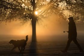 A man walks through fog as the sun rises.