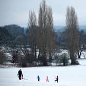 Family play on snow covered hill.
